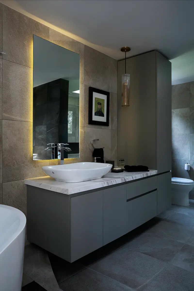 A bathroom sink decorated with dark gray stone, facing the mirror